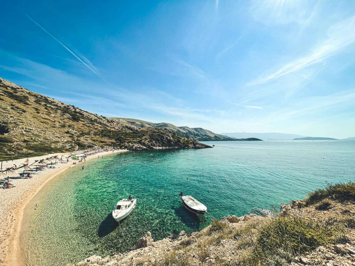 Strandolók az Adriai-tenger türkizkék partján Horvátországban, ahol online ellenőrizhető a vízminőség
