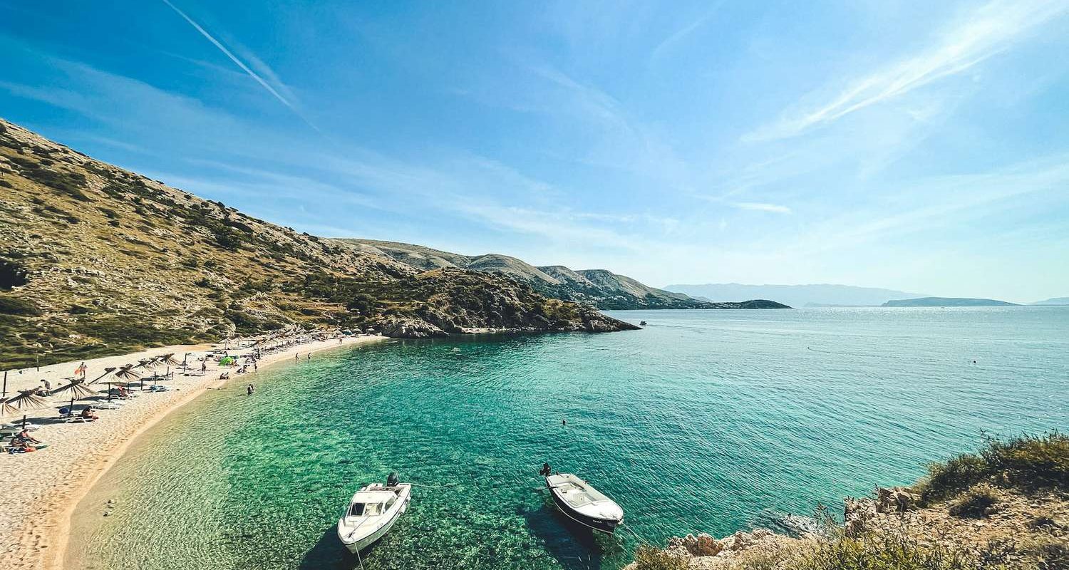 Strandolók az Adriai-tenger türkizkék partján Horvátországban, ahol online ellenőrizhető a vízminőség