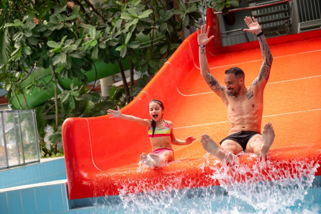 Apa és gyermeke együtt csúszdázik a Debrecen Aquaticum SPA Mediterrán Élményfürdőjében.